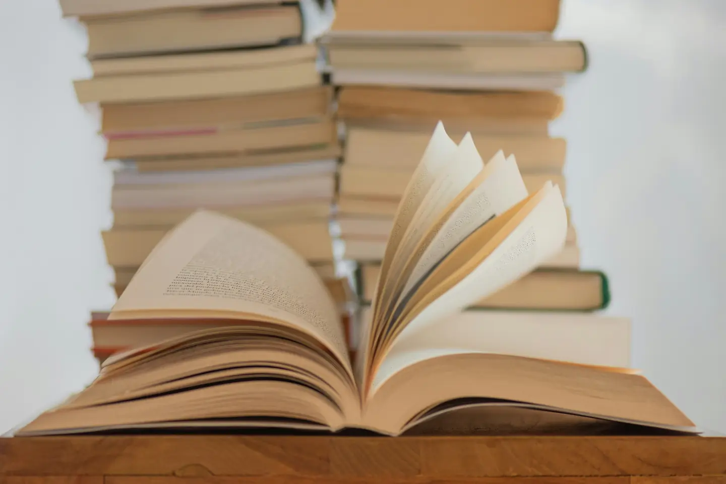 Раскрытая книга на столе на фоне стопок книг