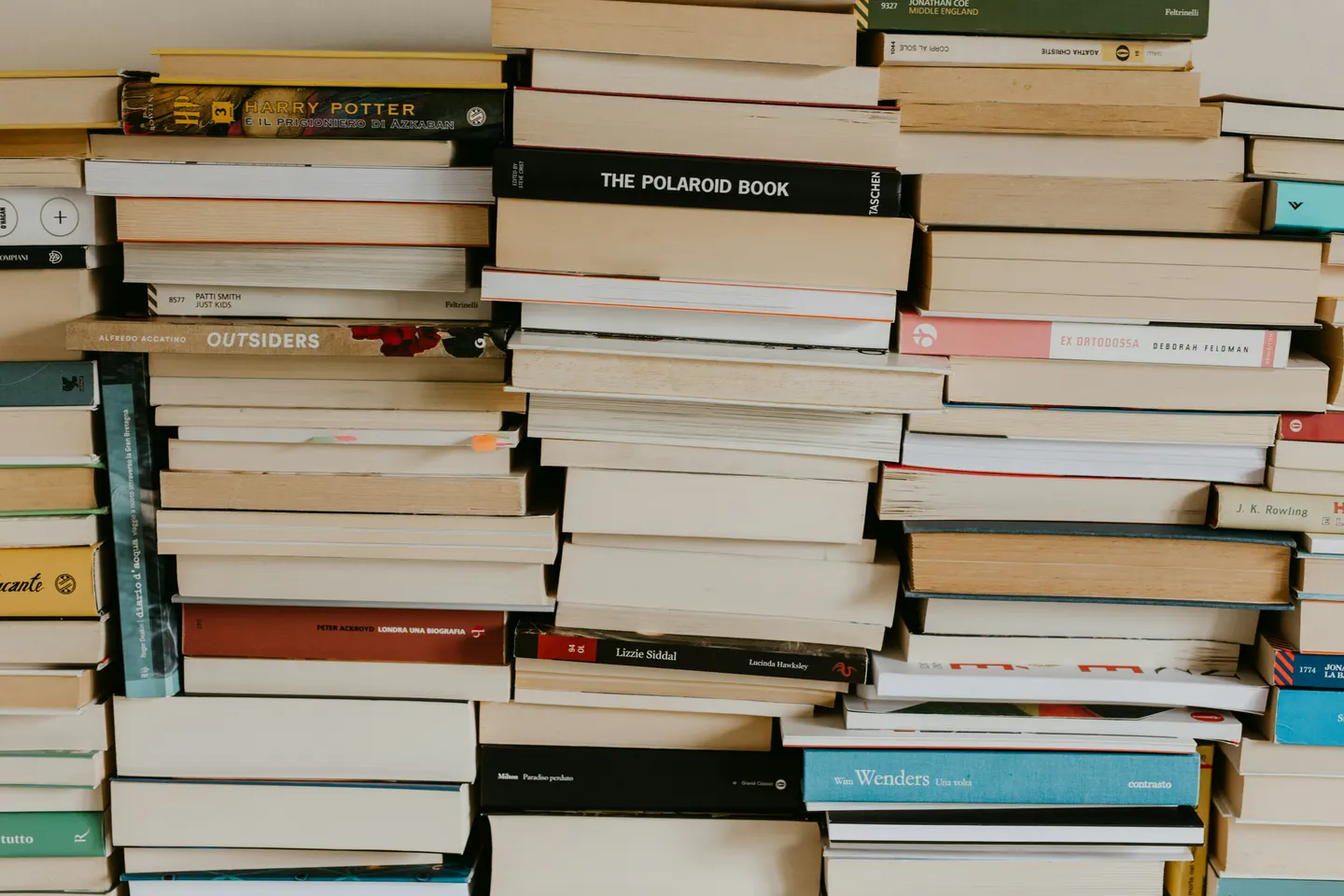 Стопки книг в разноцветных переплётах, сложенные корешками наружу от пола до потолка